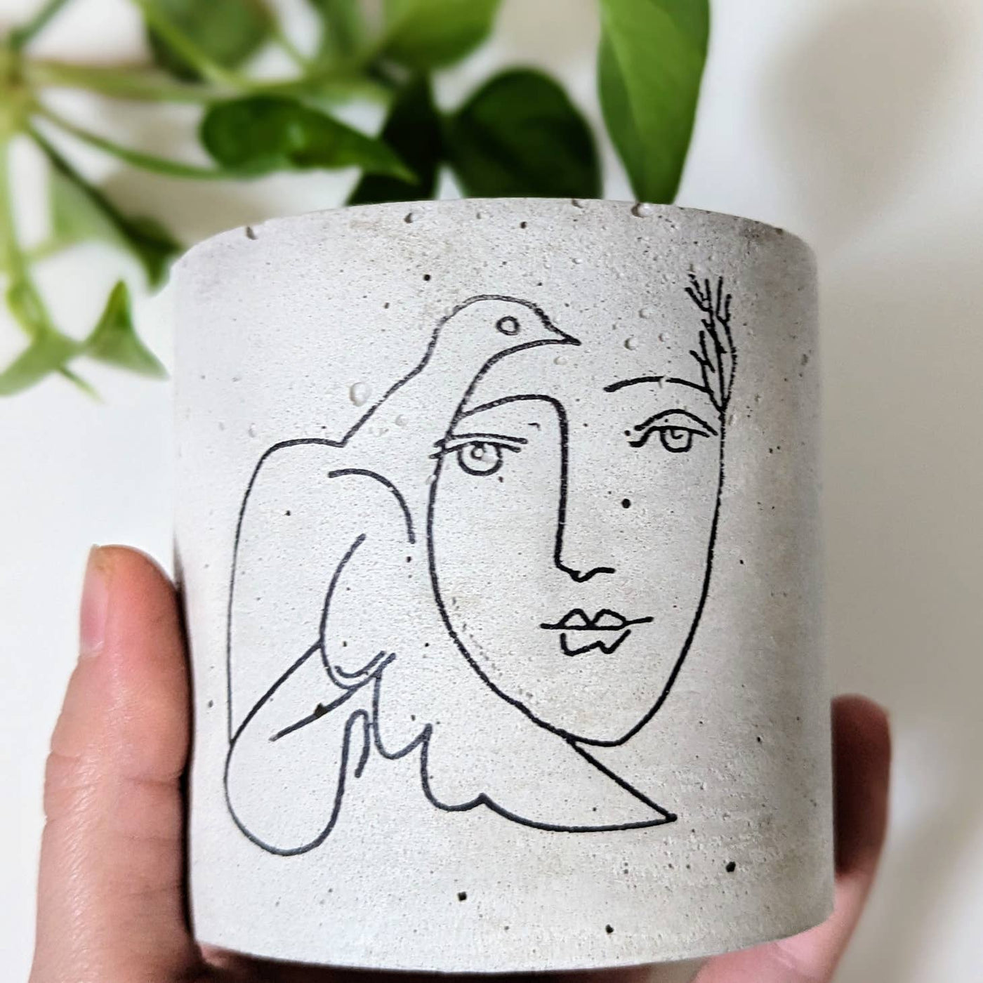 Picasso's dove and woman outline painted on a concrete planter