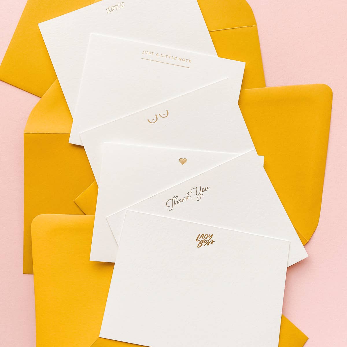 assorted white flat notes with small gold foil detailing on each against mustard yellow envelopes