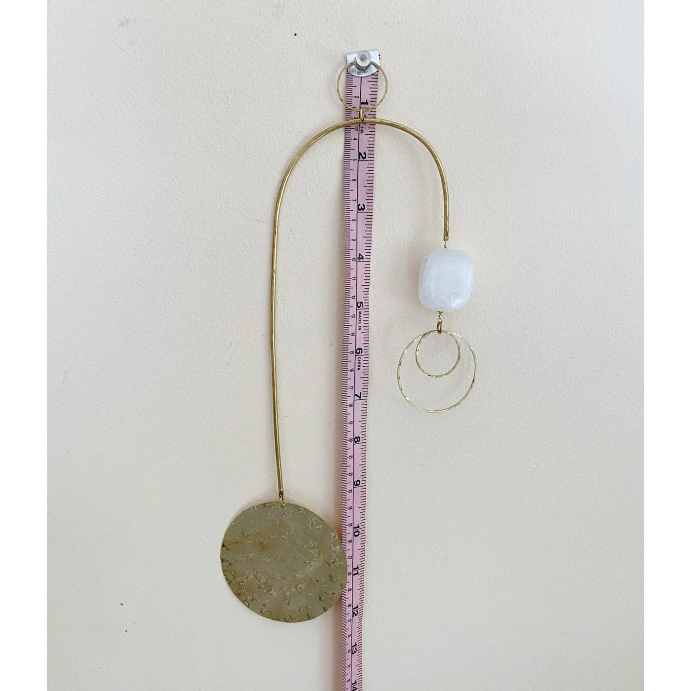 wall hanging with brass disc and selenite stone, shown with a measuring tape for exact dimensions