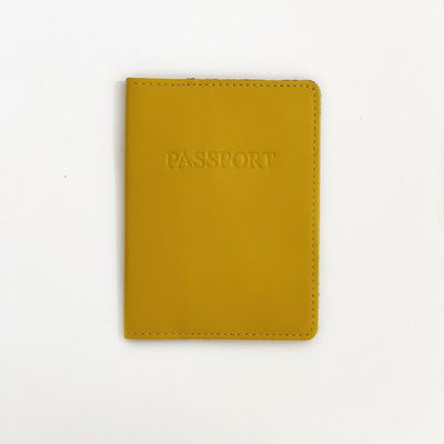Front of mustard yellow passport case with "PASSPORT" engraved in all caps in the center top of the cover