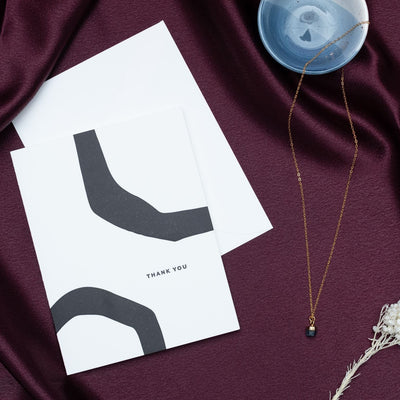 thank you card with a necklace in a ring bowl