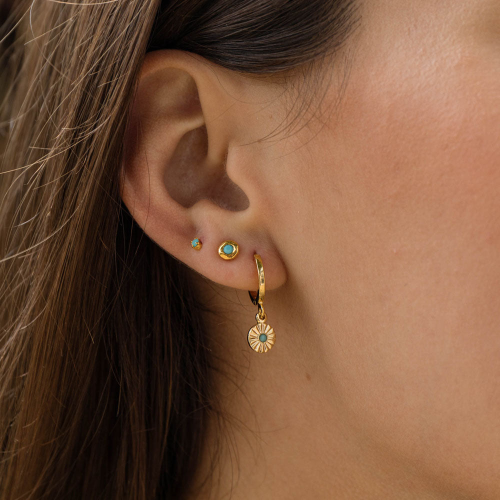 model wearing tiny turquoise gold stud earrings