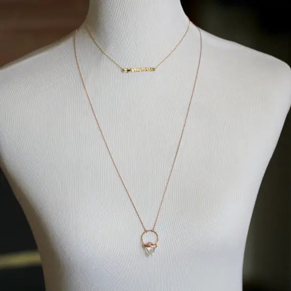 14k gold fill necklace with a raw diamond, shown on a bust with another necklace for scale