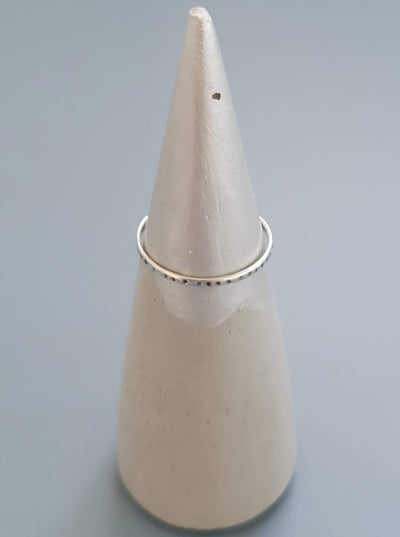 Concrete ring cone dipped in silver paint at the top; holding a ring