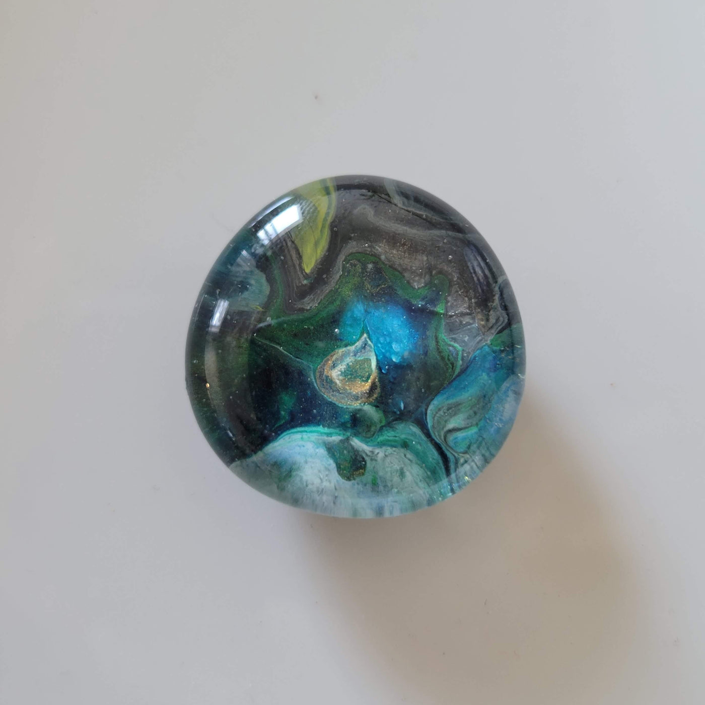 hand-painted circular glass magnet with shades of blue and green swirled