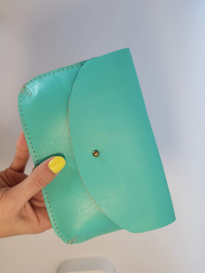 Model hand holding aqua color leather wallet to scale; wallet length is approximately double the palm size of the model