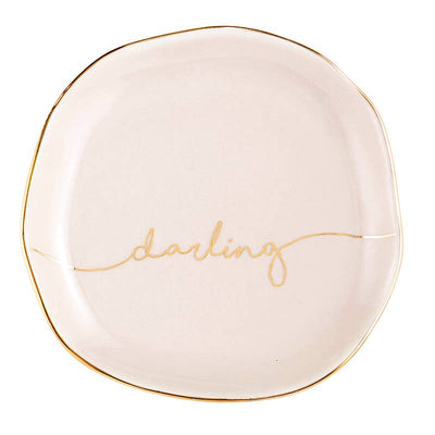 Light pink circular trinket tray with gold trim and cursive "darling" printed in the center