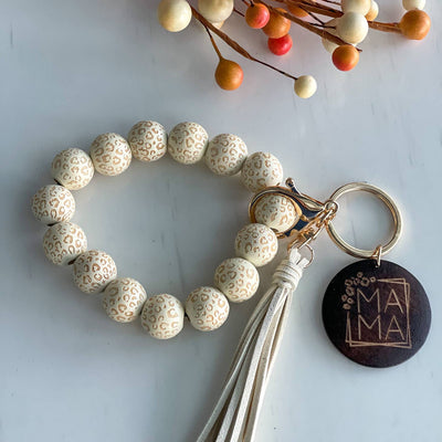 wooden beaded wristlet keychain with tassel and wooden disc that reads, "mama", colors are cream with leopard print