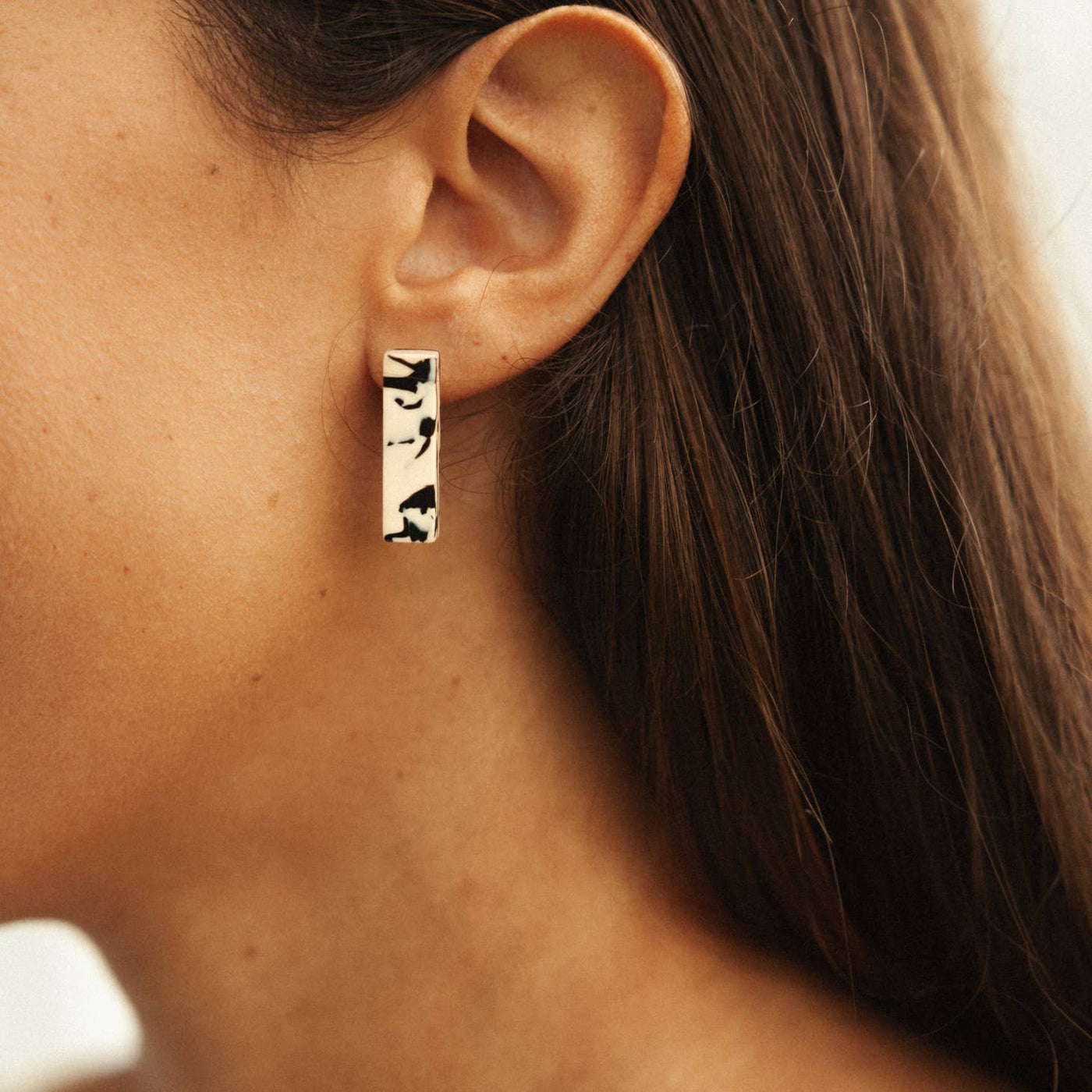 organic pattern cream and black acetate bar earrings on model close up