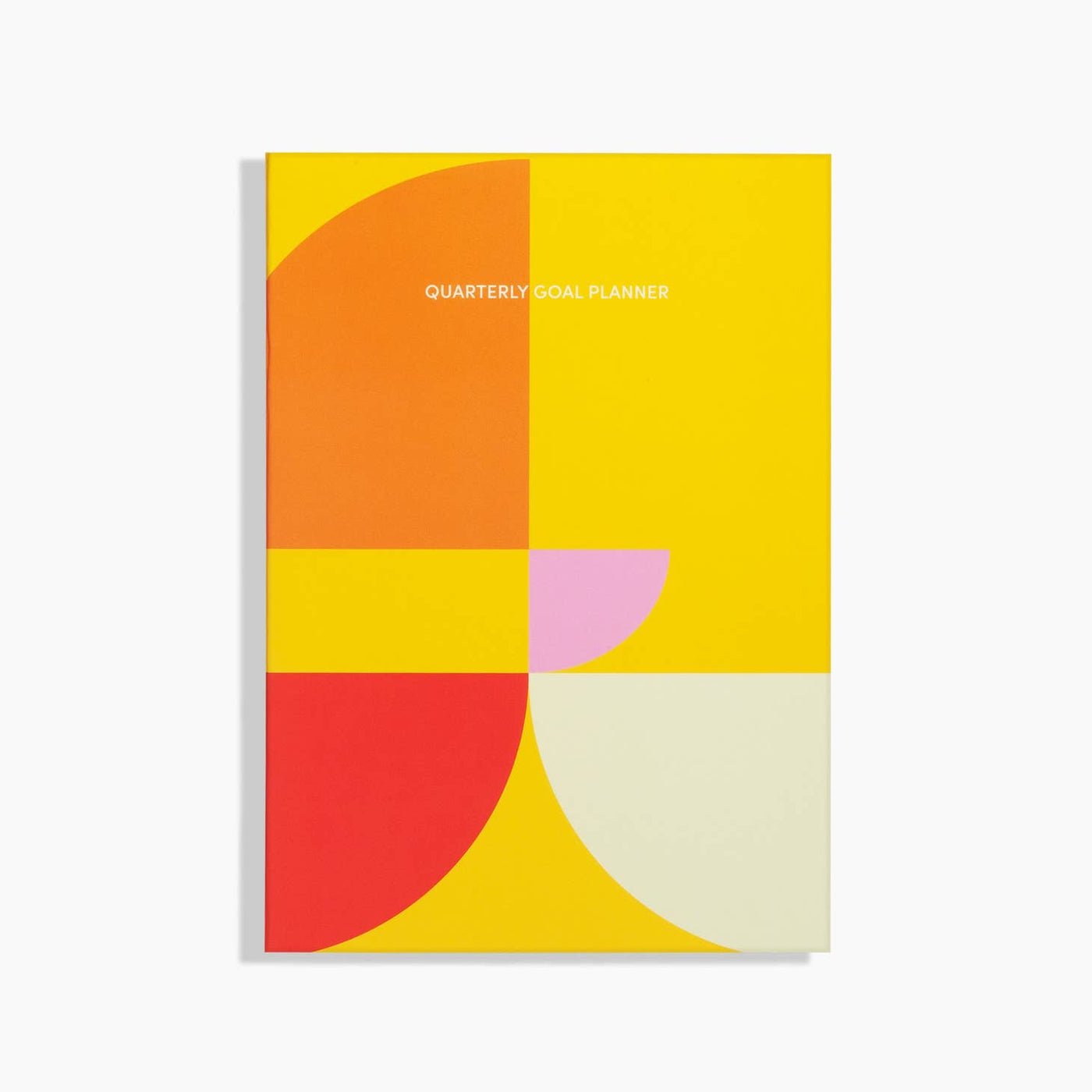 Front cover of quarterly goal planner; colorblock design in yellow, orange, red, pink and cream.