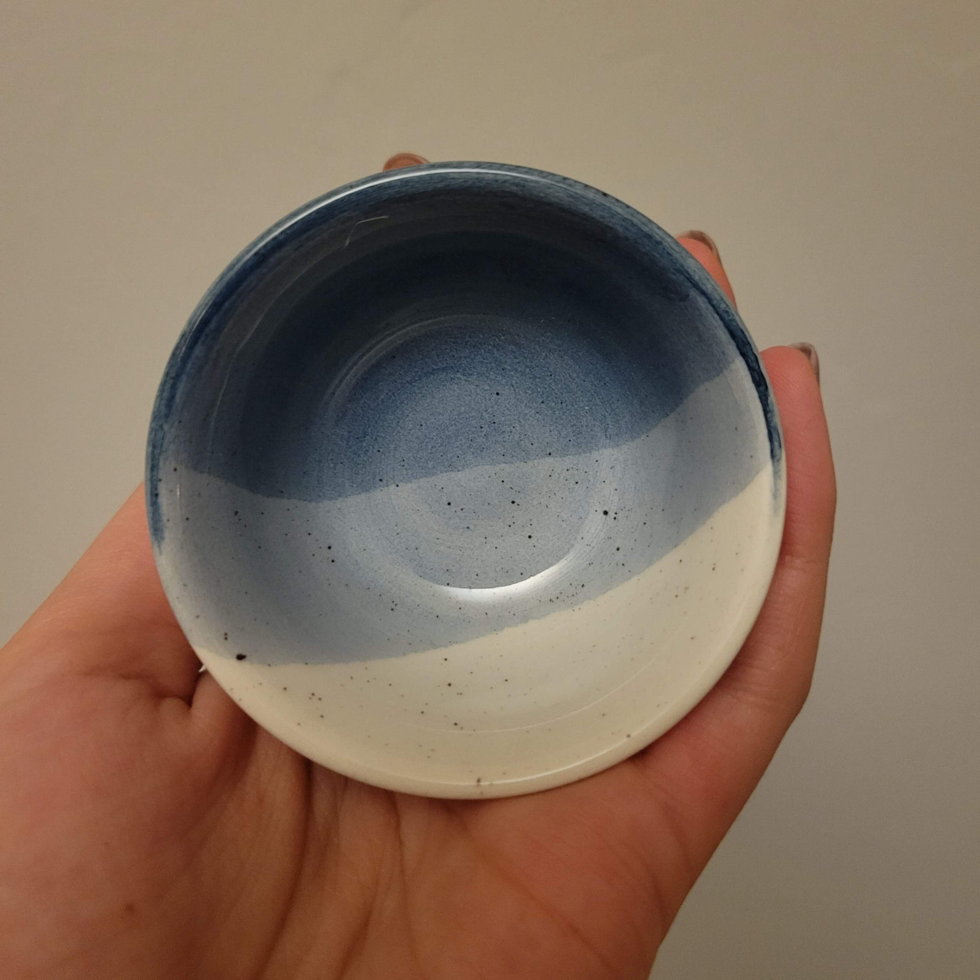 interior of small ceramic ring dish glazed in shades of blue with speckles