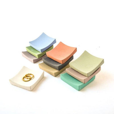 3 stacks of tiny square ring dishes in various colors with 1 white ring dish shown separately with rings on it
