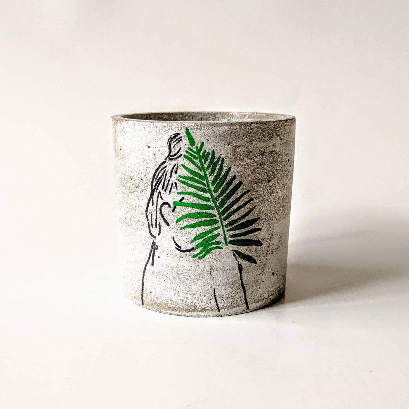Concrete planter with hand painted silhouette of a woman from the side holding a leaf in green covering her face