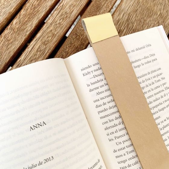 Tan leather bookmark with butter yellow color trim at top in an open book