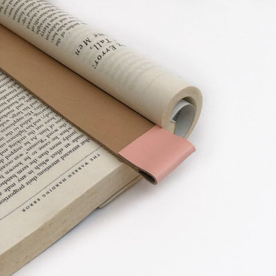 Close up of tan leather bookmark with light pink color trim at top in an open book